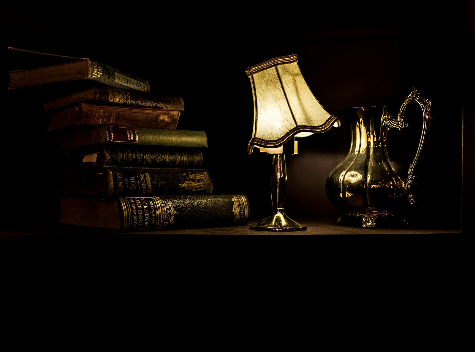 A lamplit reading room — aged books beside a warm lamp